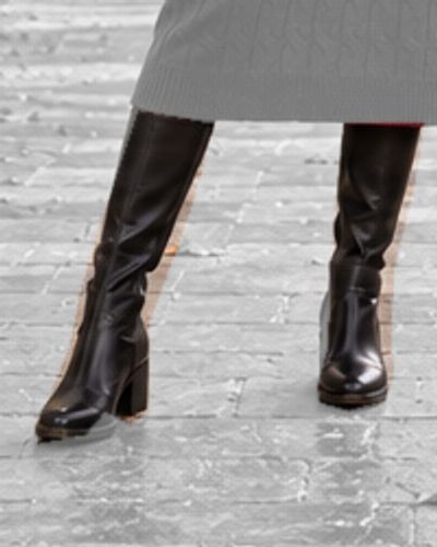 Détail de l’illustration IA : bottes noires sous l’ourlet de la robe rouge.